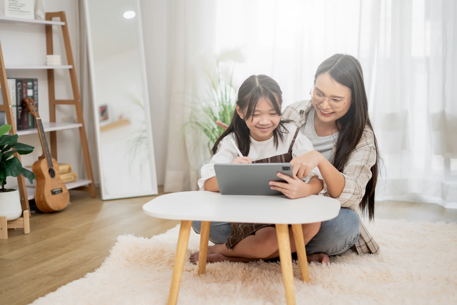 A mother and daughter looking at a tablet together at home
