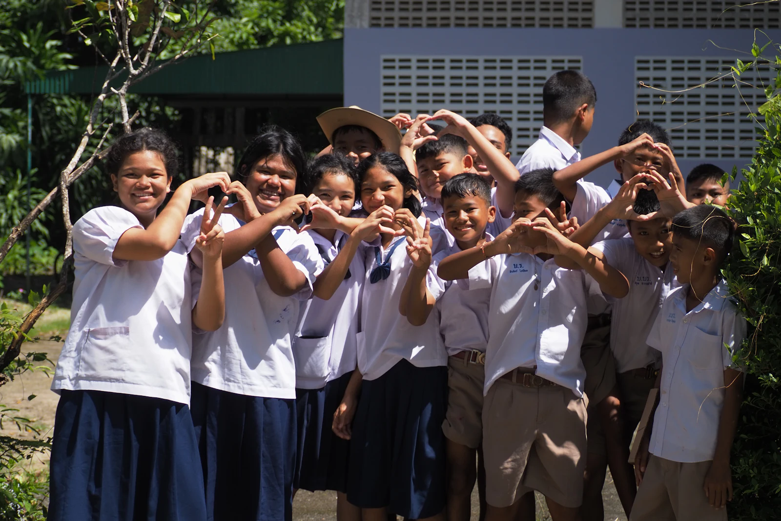 Primary school pupils in uniform making heart shapes with their hands