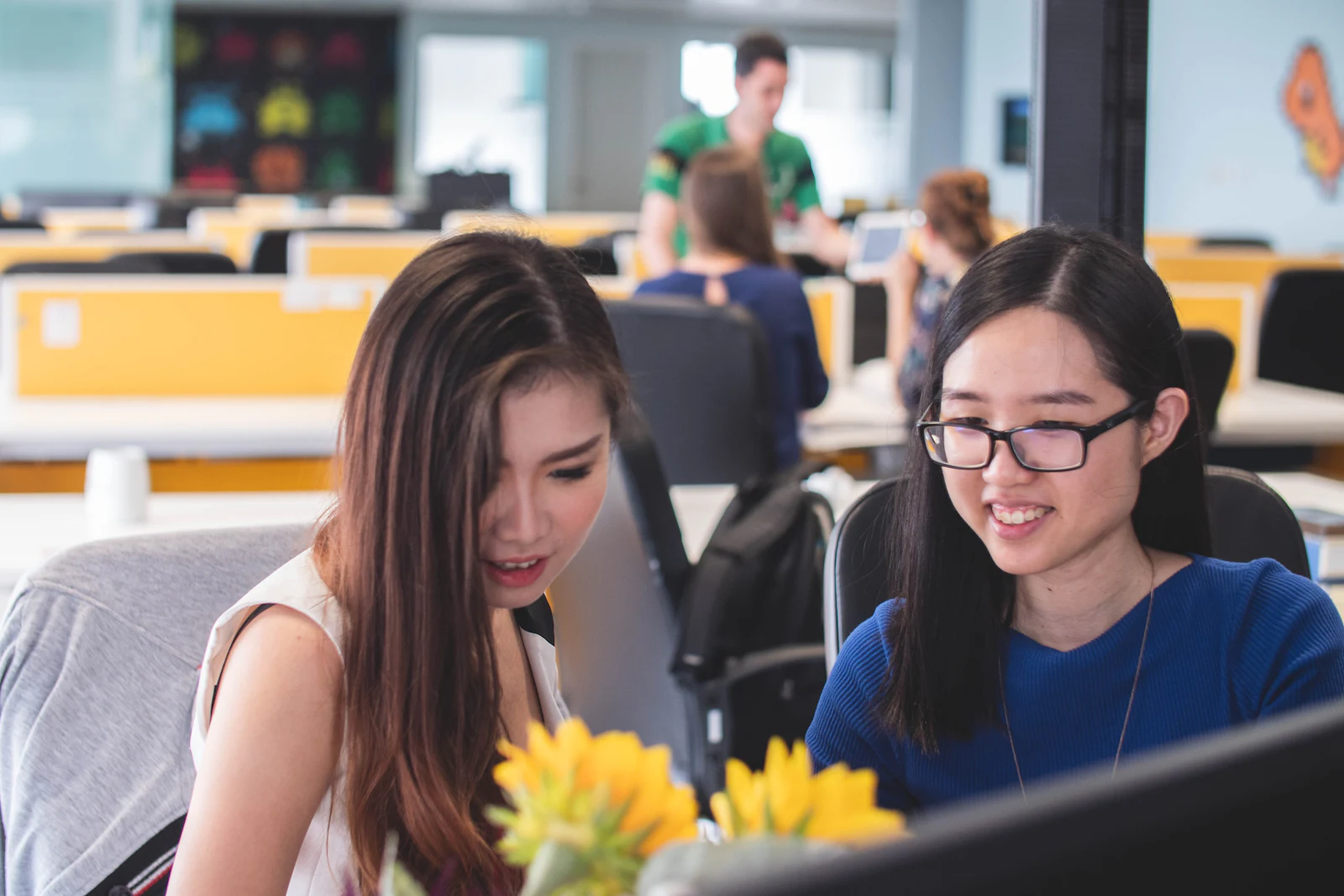 Two colleagues working together and smiling at an office desk